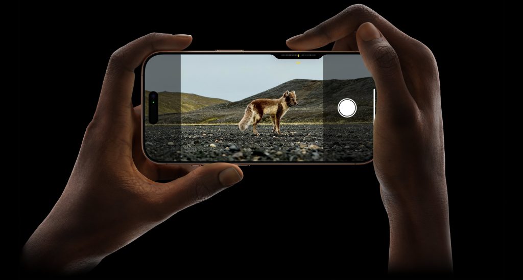 An iPhone 16 is held by two hands horizontally, and on the screen is an image of a wolf. The sharpening tool in the photo program is highlighting the wolf subject and making it contrasted deeply, sharpening the image. 