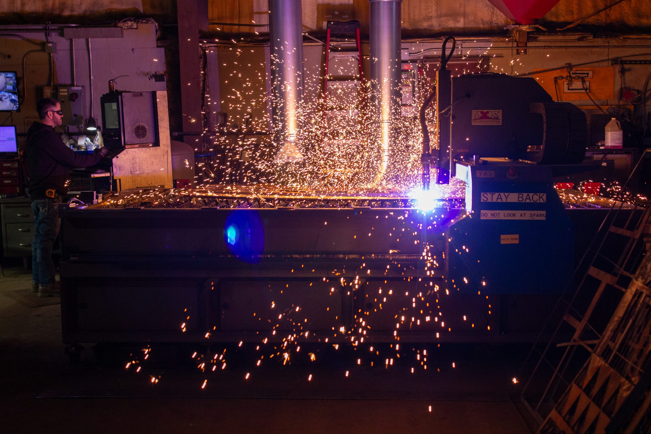 Plasma Cutting machine in action throwing sparks as it cuts a design into a metal sheet at Rescued Metals.